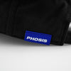 Load image into Gallery viewer, Close up view of the woven label in the VISIONS black dad hat from PHOSIS® Clothing