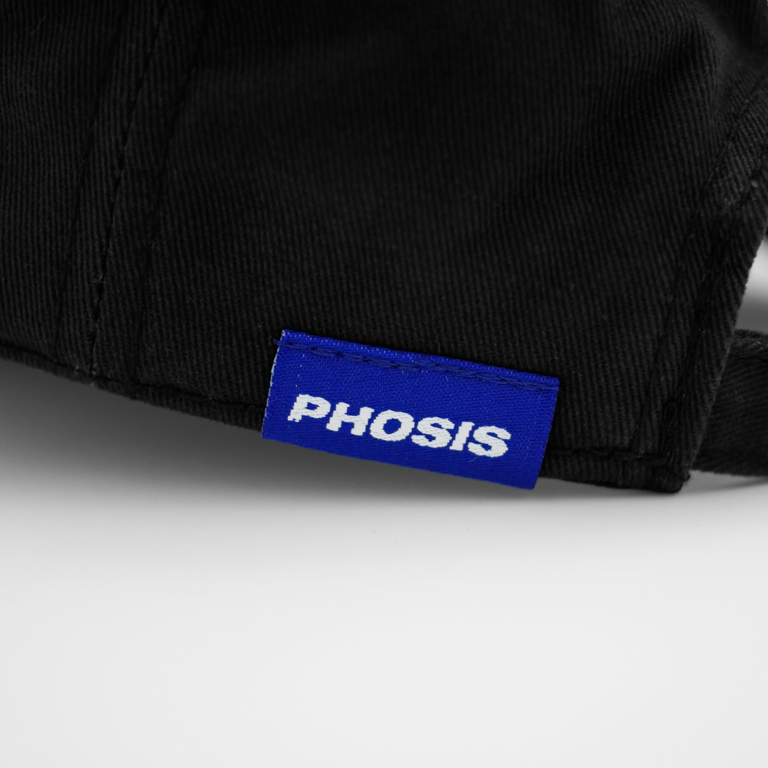 Close up view of the woven label in the MOB black dad hat from PHOSIS® Clothing