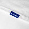 Close up view of the blue woven label in the VISIONS white long sleeve from PHOSIS® Clothing