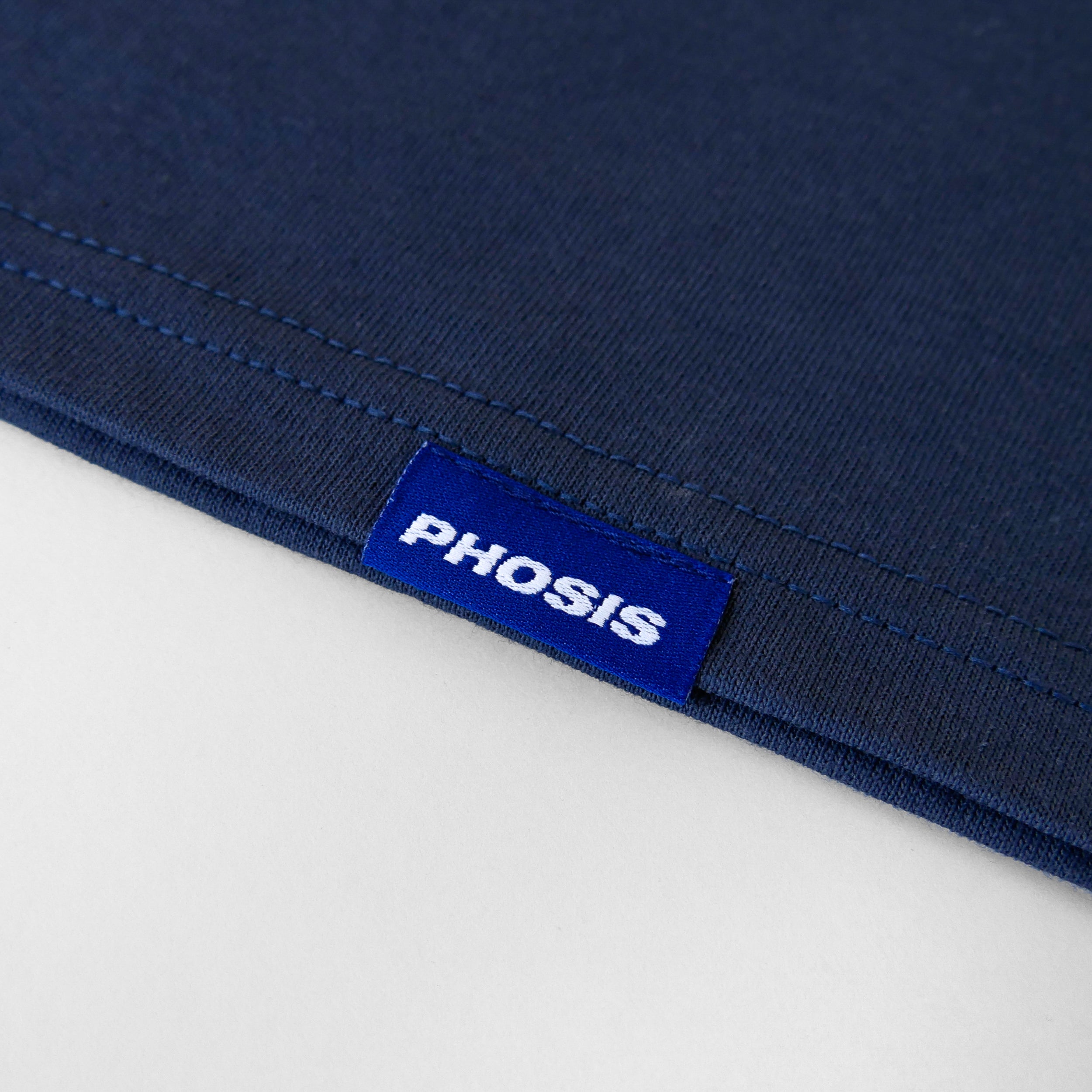 Close up view of the blue woven label in the HYPERLINK indigo blue heavyweight cotton t-shirt from PHOSIS® Clothing